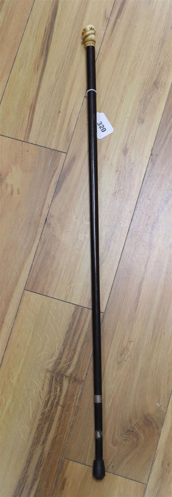 An ebonised walking cane, the handle of a carved ivory hand holding a coiled serpent, length 87cm